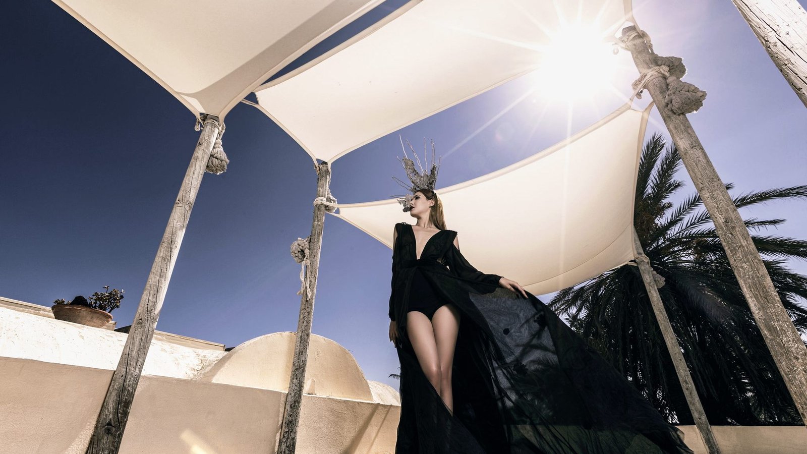 Black tulle gown photographed beneath rooftop sails in hard sunlight
