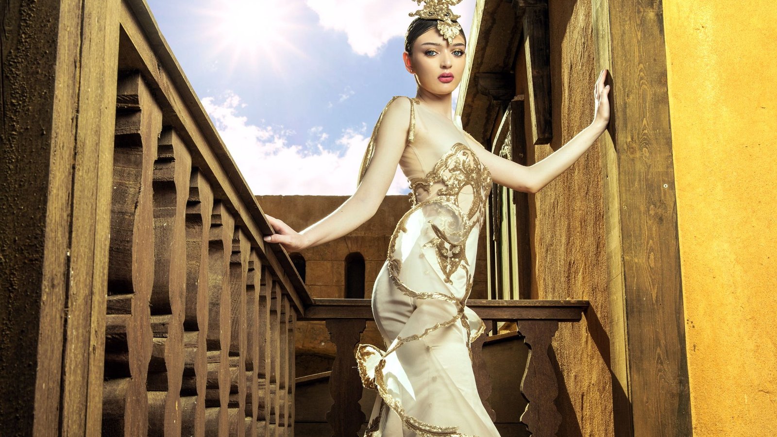Gold-embroidered gown photographed on a carved wooden staircase