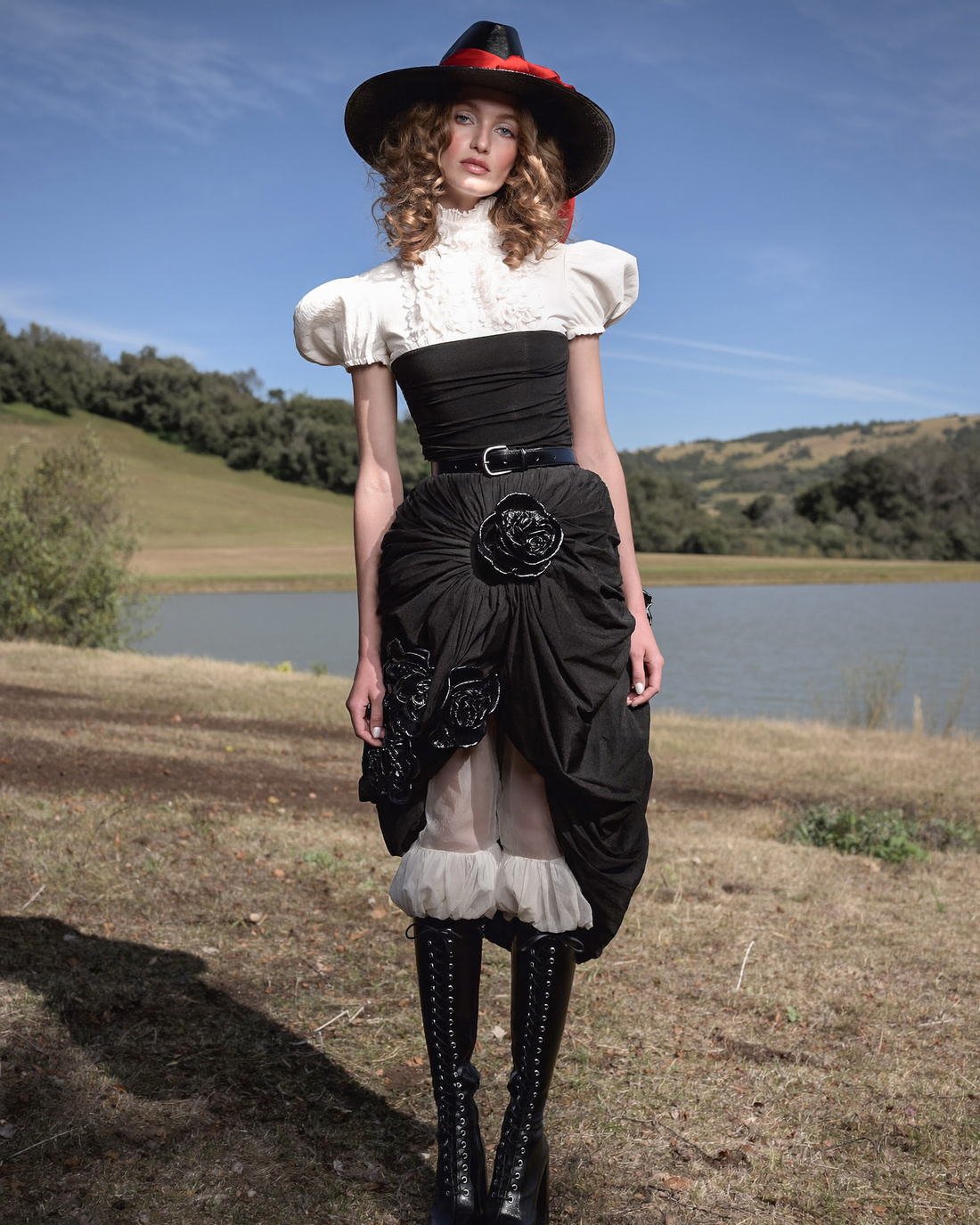 Corseted black skirt and blouse in open landscape, Vestiges