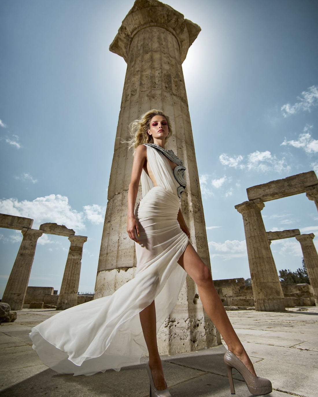 White gown against stone columns and blue sky, Fragments of a Forgotten Queen
