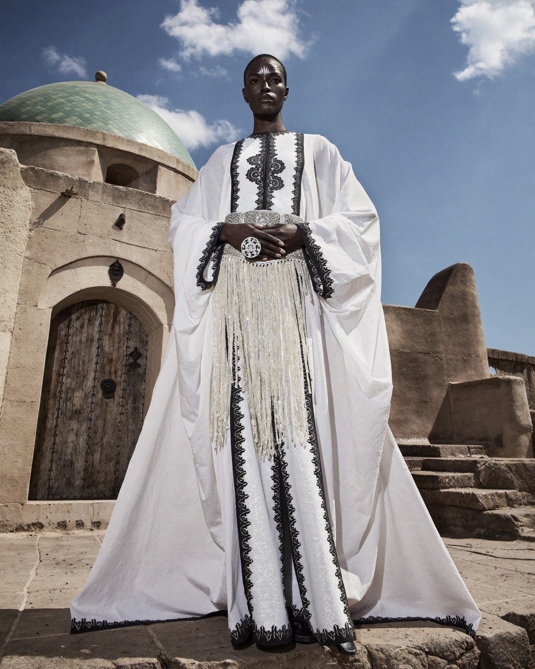Long embroidered coat in an archway, Daughter of the Wind