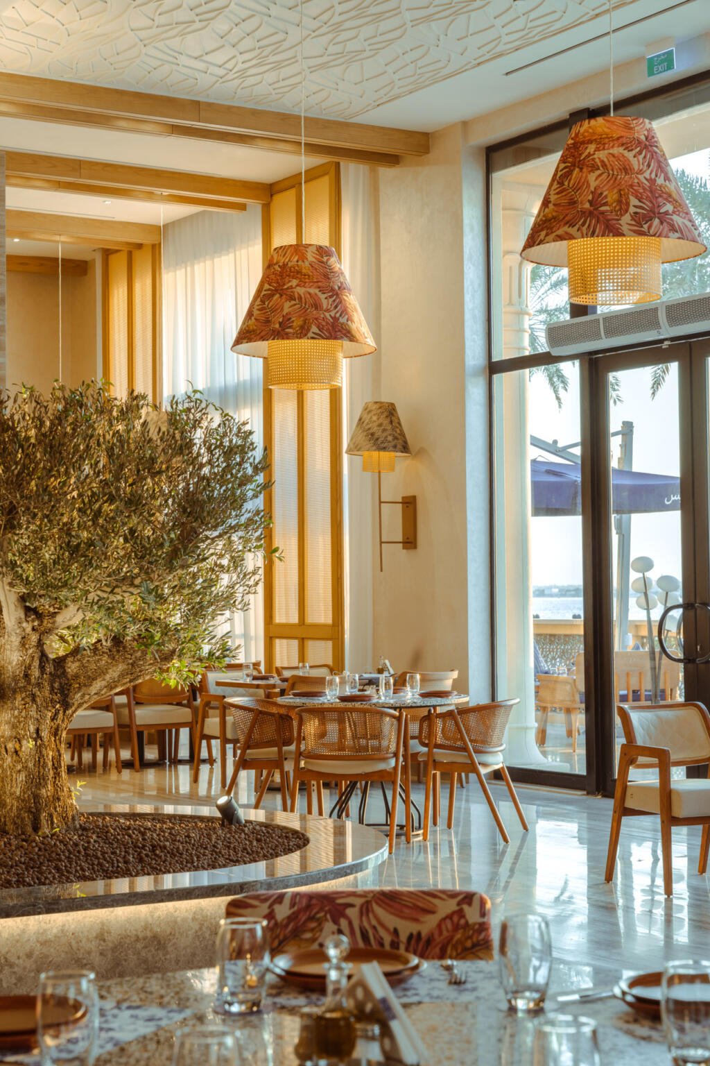 Olive tree planted in a lit marble planter at the centre of the Loris dining room