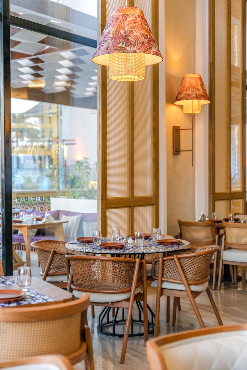 Round dining tables beneath lanterns in printed fabric at Loris