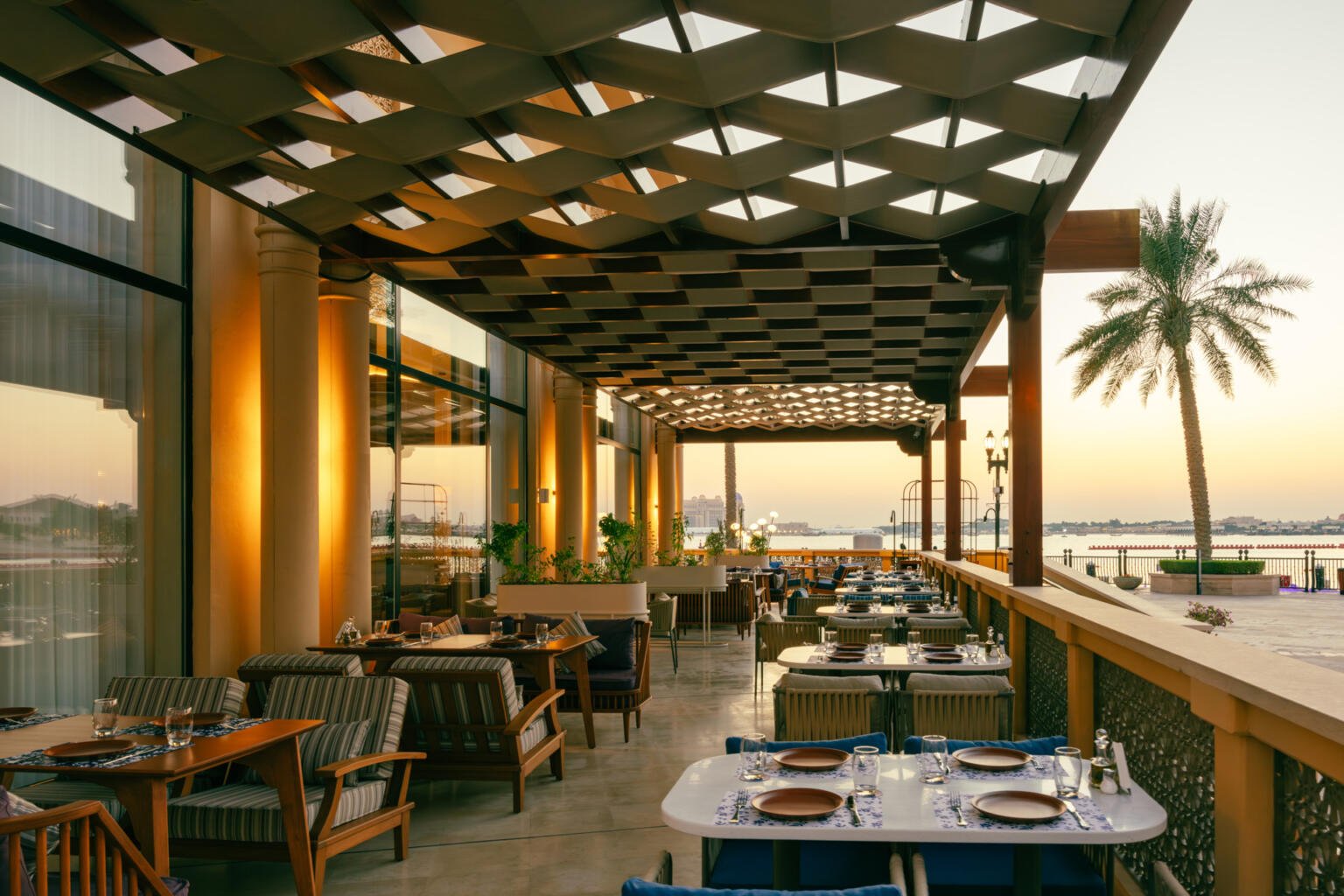 A private waterfront venue in Doha: the Loris terrace at sunset under its timber lattice ceiling, from a commissioned shoot