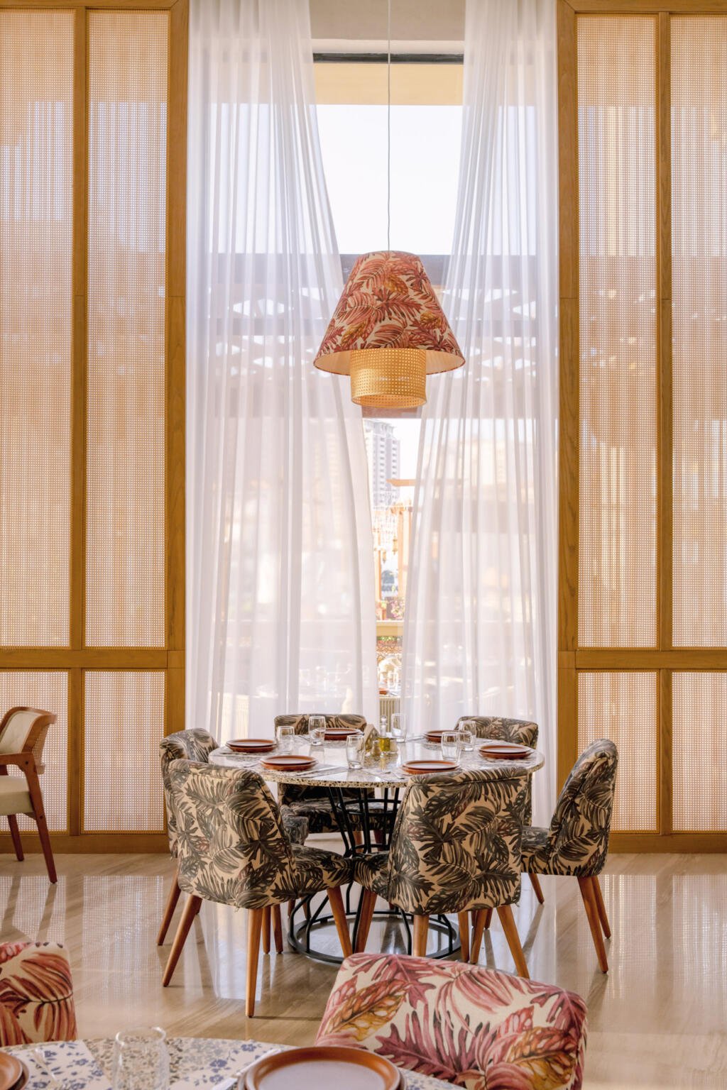 Patterned dining chairs around a round table under a lantern at Loris