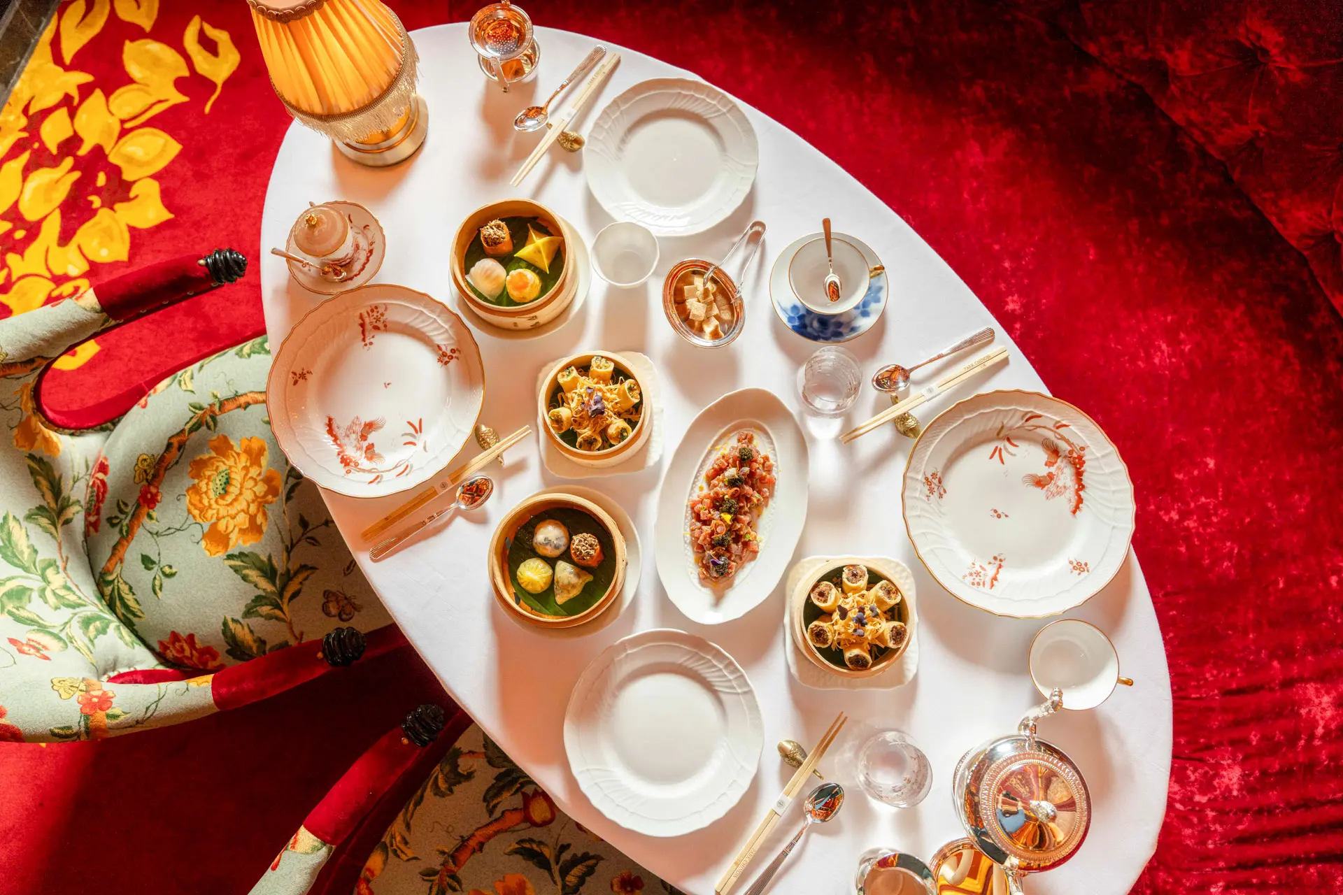 Fine-dining table from above with porcelain and small plates on red cloth