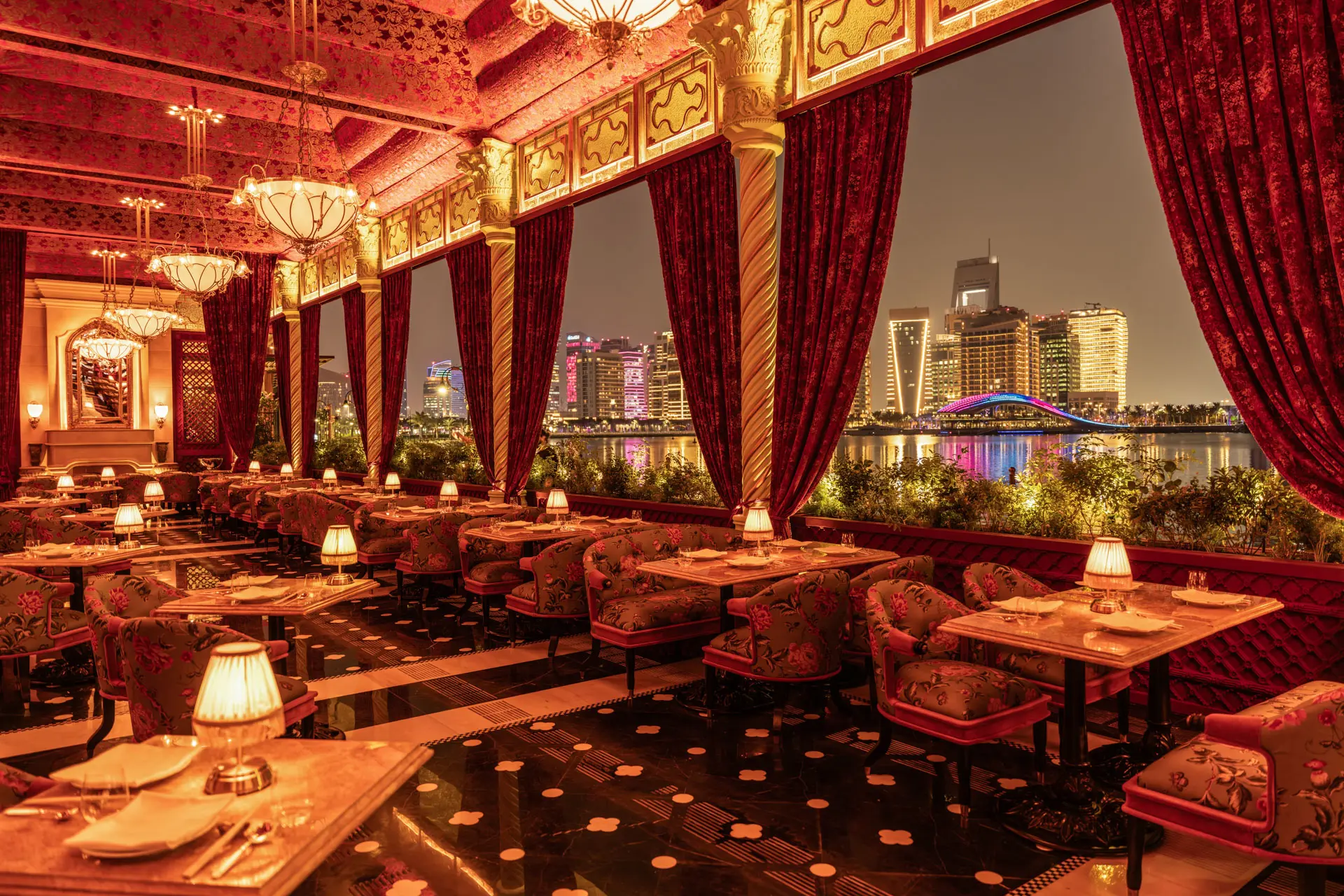 Opulent red restaurant interior with chandeliers and a city view