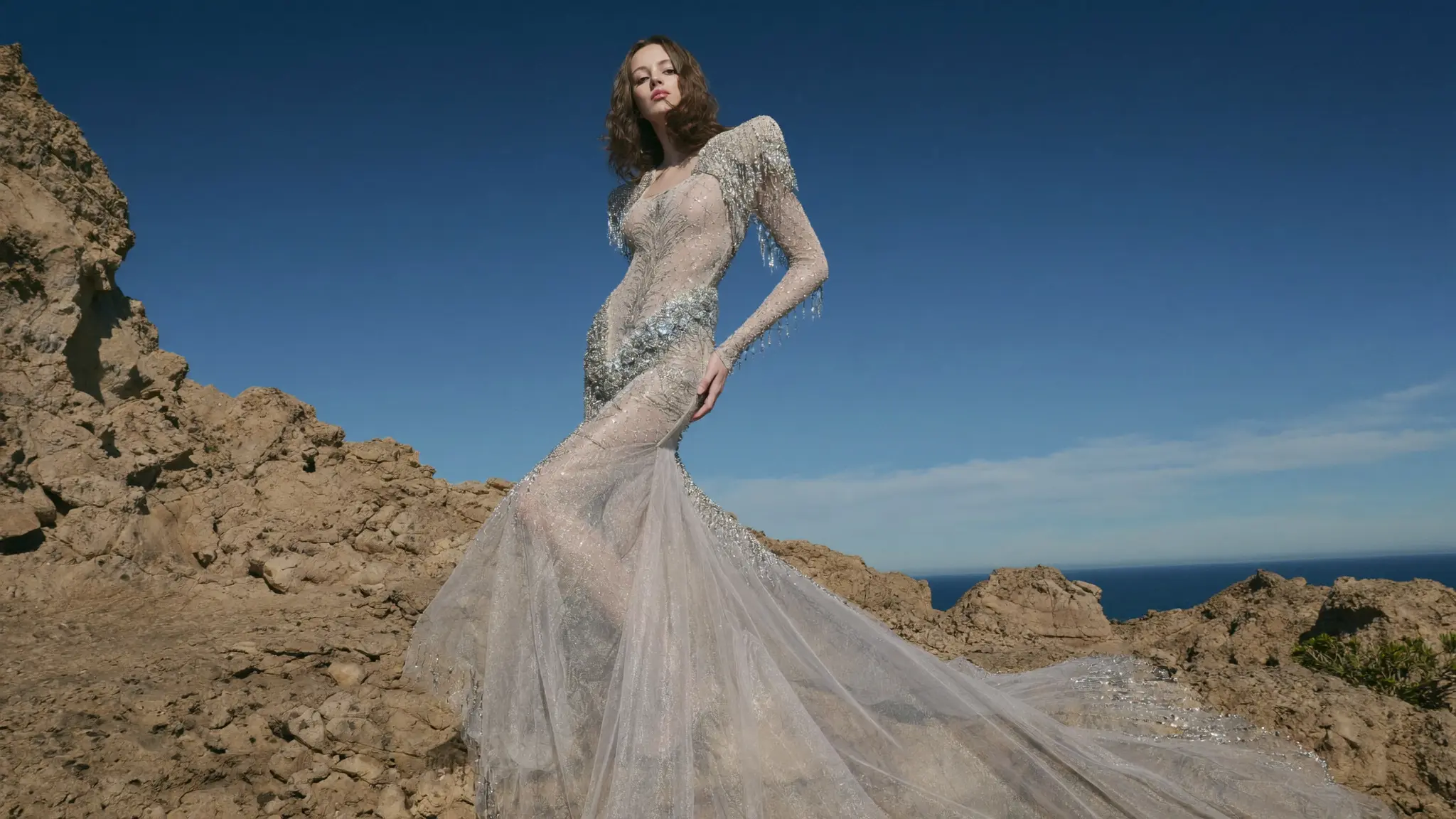 Bride in a lace gown on coastal rocks above the sea