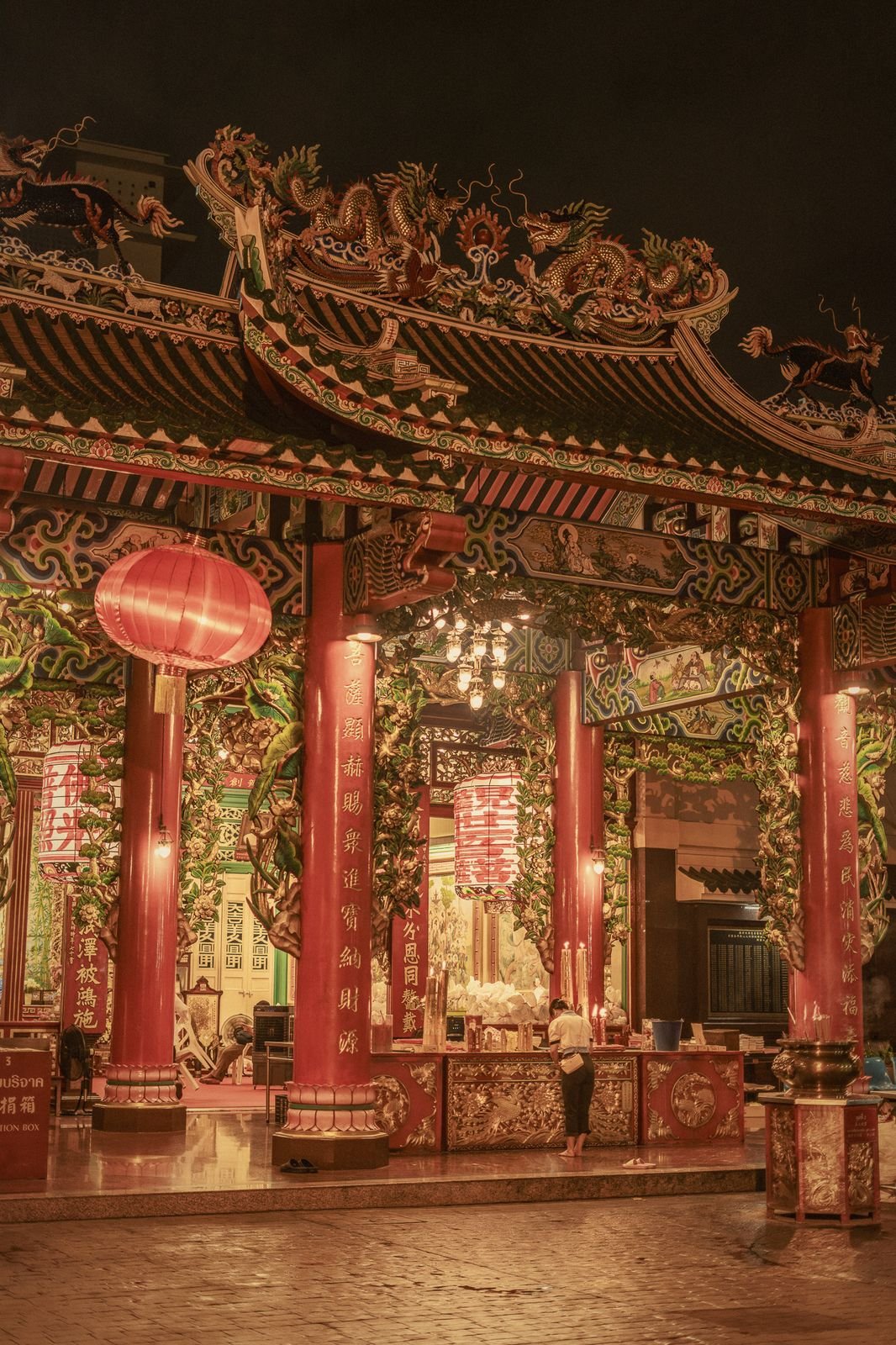 A Chinese temple facade glowing red at night in Bangkok