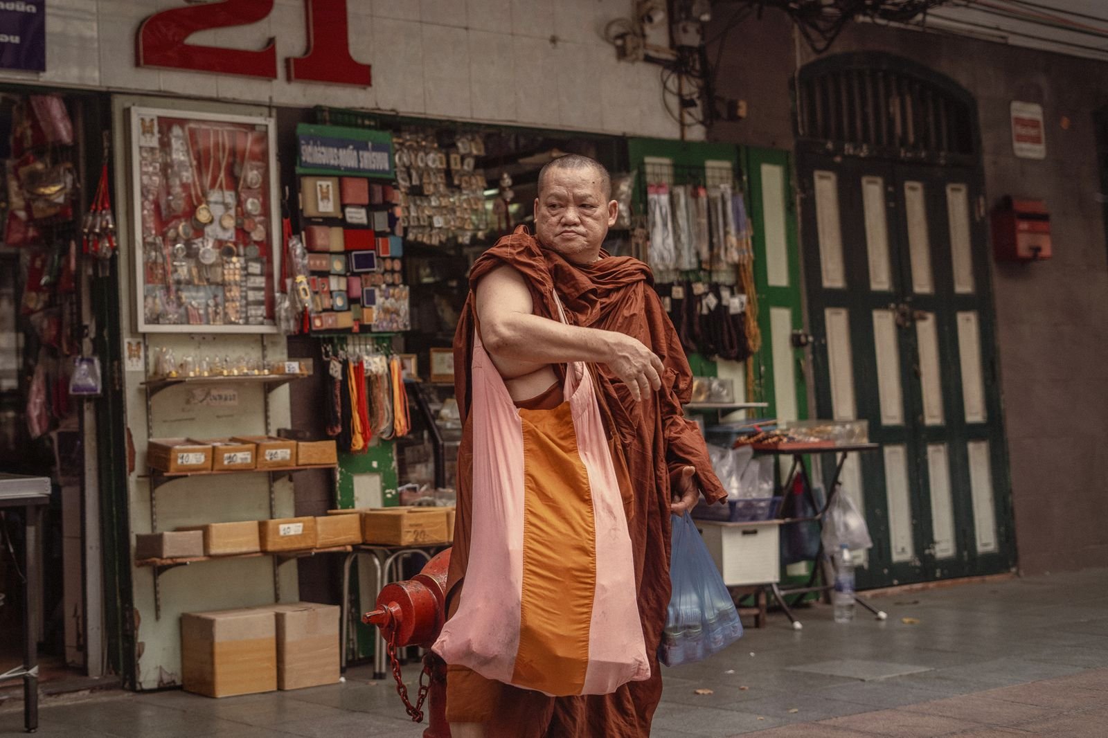 A Buddhist monk passing a shopfront in Bangkok