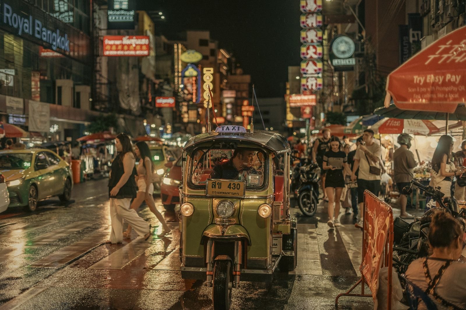 A tuk-tuk on the rain-wet streets of Bangkok Chinatown at night