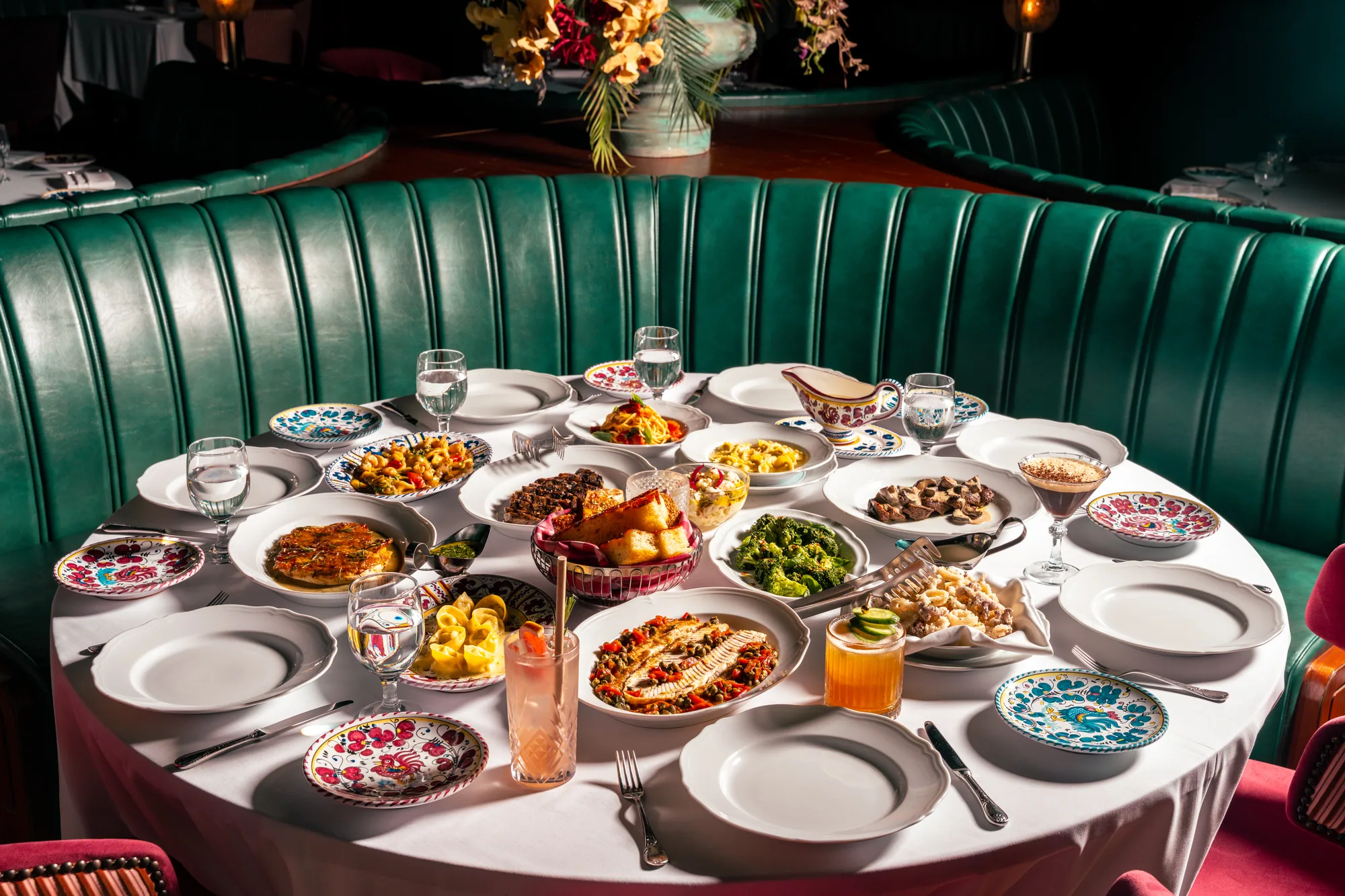 Full table of the new Carbone Doha menu in a green leather booth