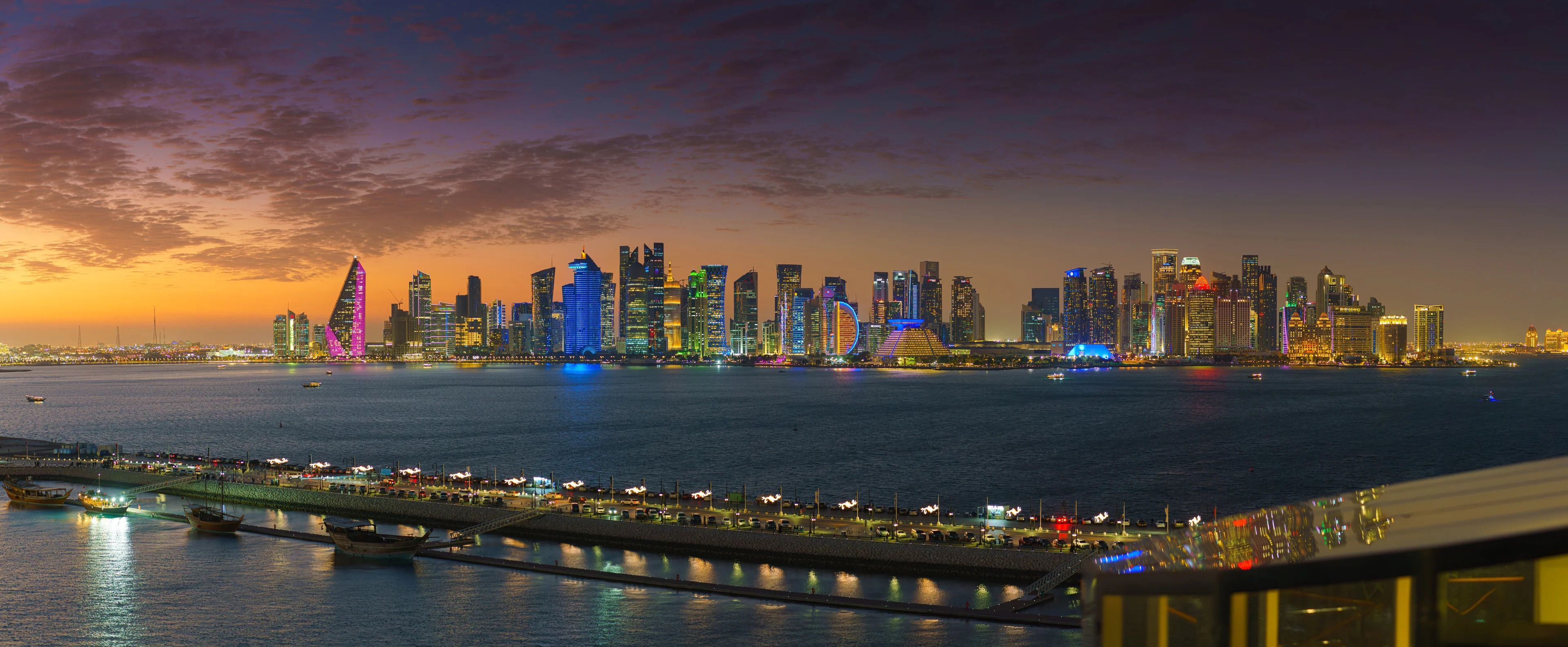 Doha skyline and Corniche at dusk, West Bay towers lit across the bay