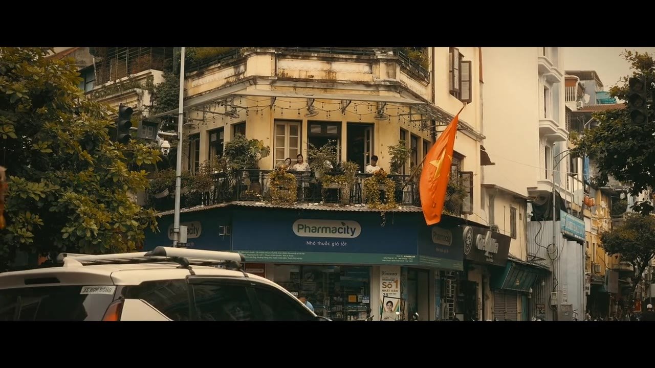 Hanoi street corner with balconies and a flag, poster frame from the Hanoi travel film