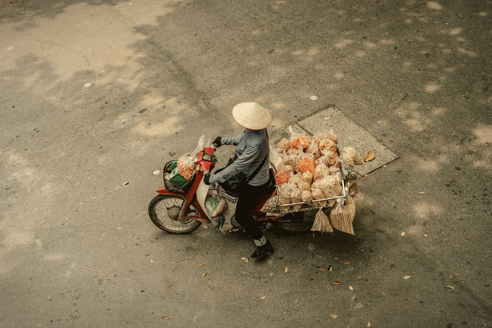 A flower seller pushing her bicycle, seen from above, in Hanoi, Vietnam