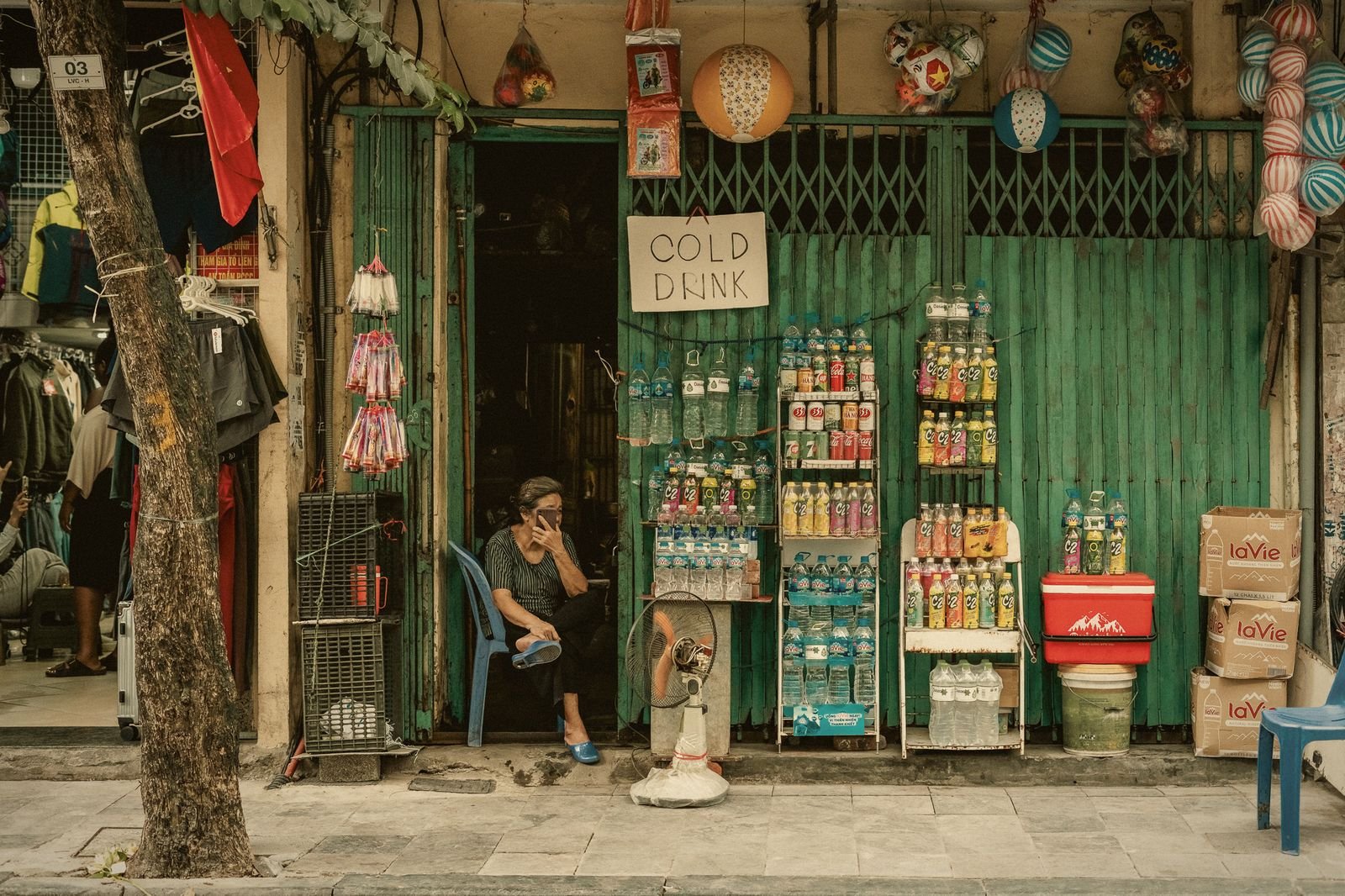 A green shopfront with a seated shopkeeper in the Hanoi Old Quarter