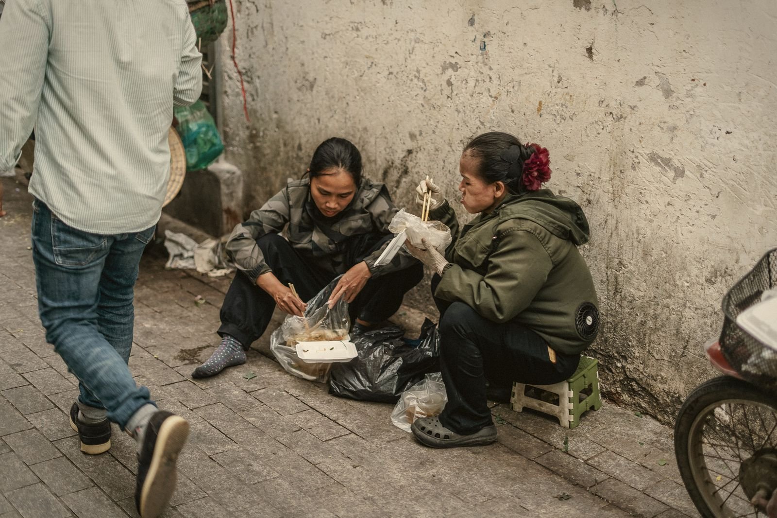 Two women sharing lunch on a Hanoi pavement, Vietnam