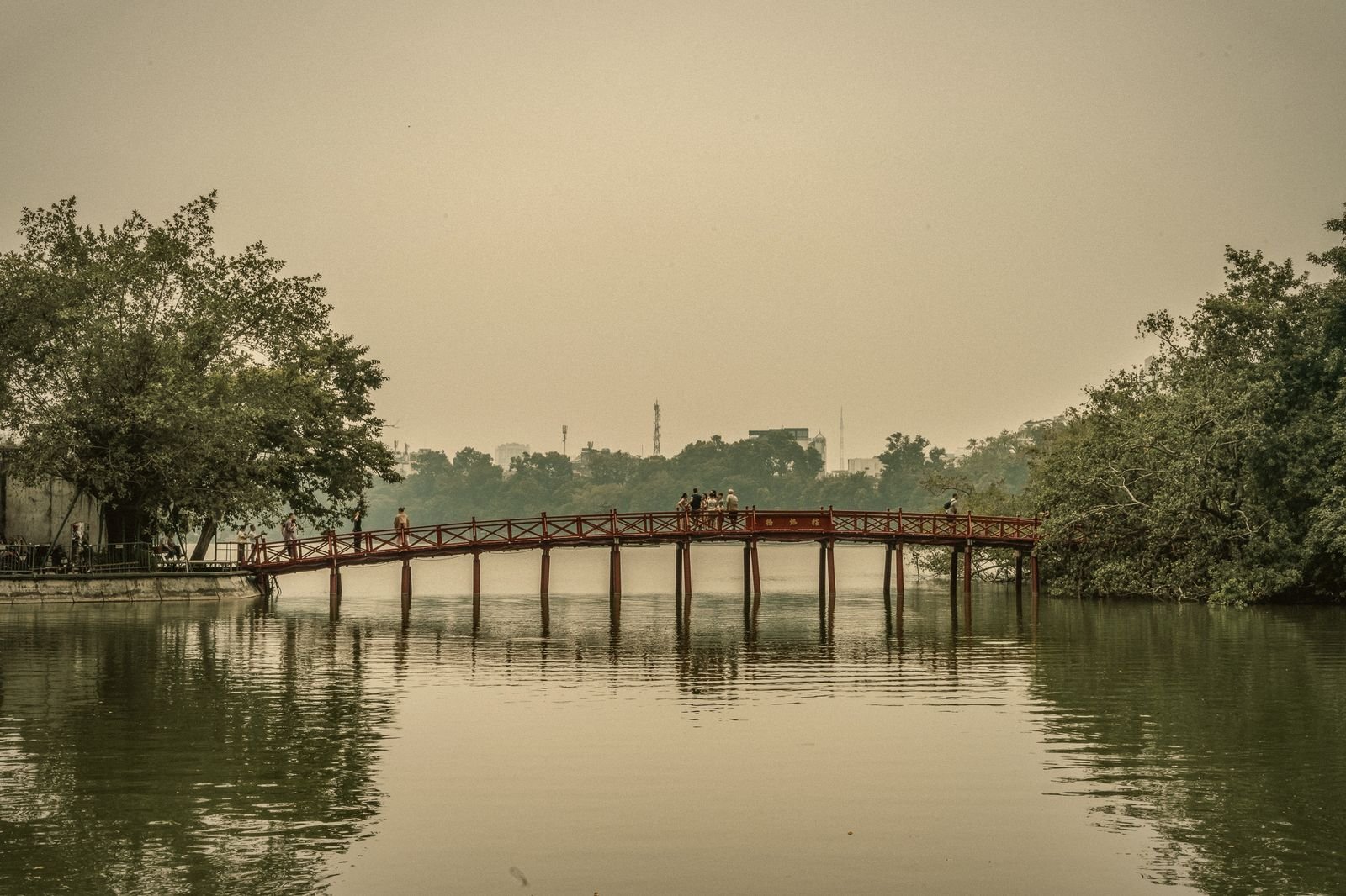 The red The Huc bridge over Hoan Kiem Lake in morning haze