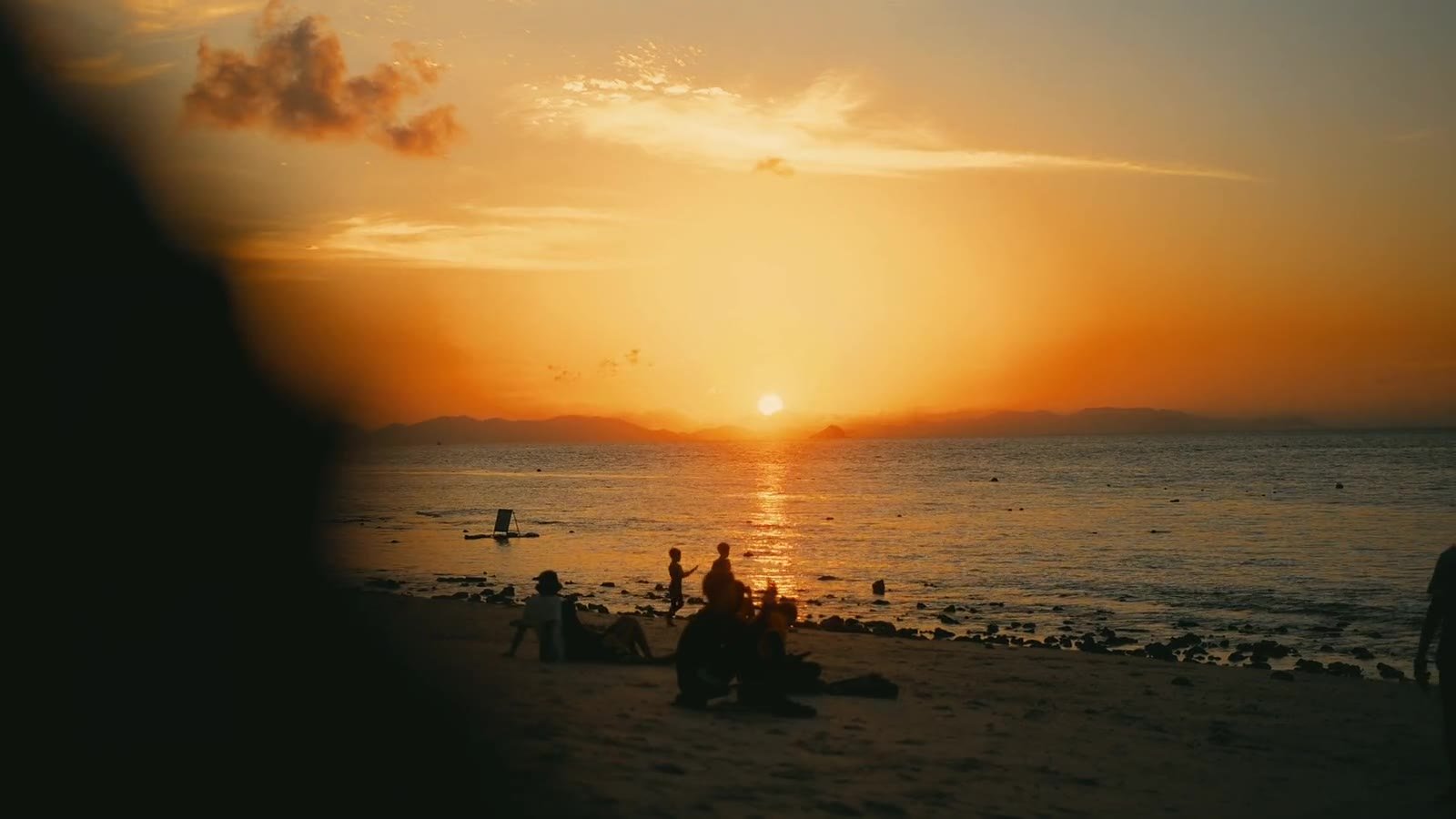Sunset over the sea with figures on the shore, opening frame of the Thailand and Vietnam film series