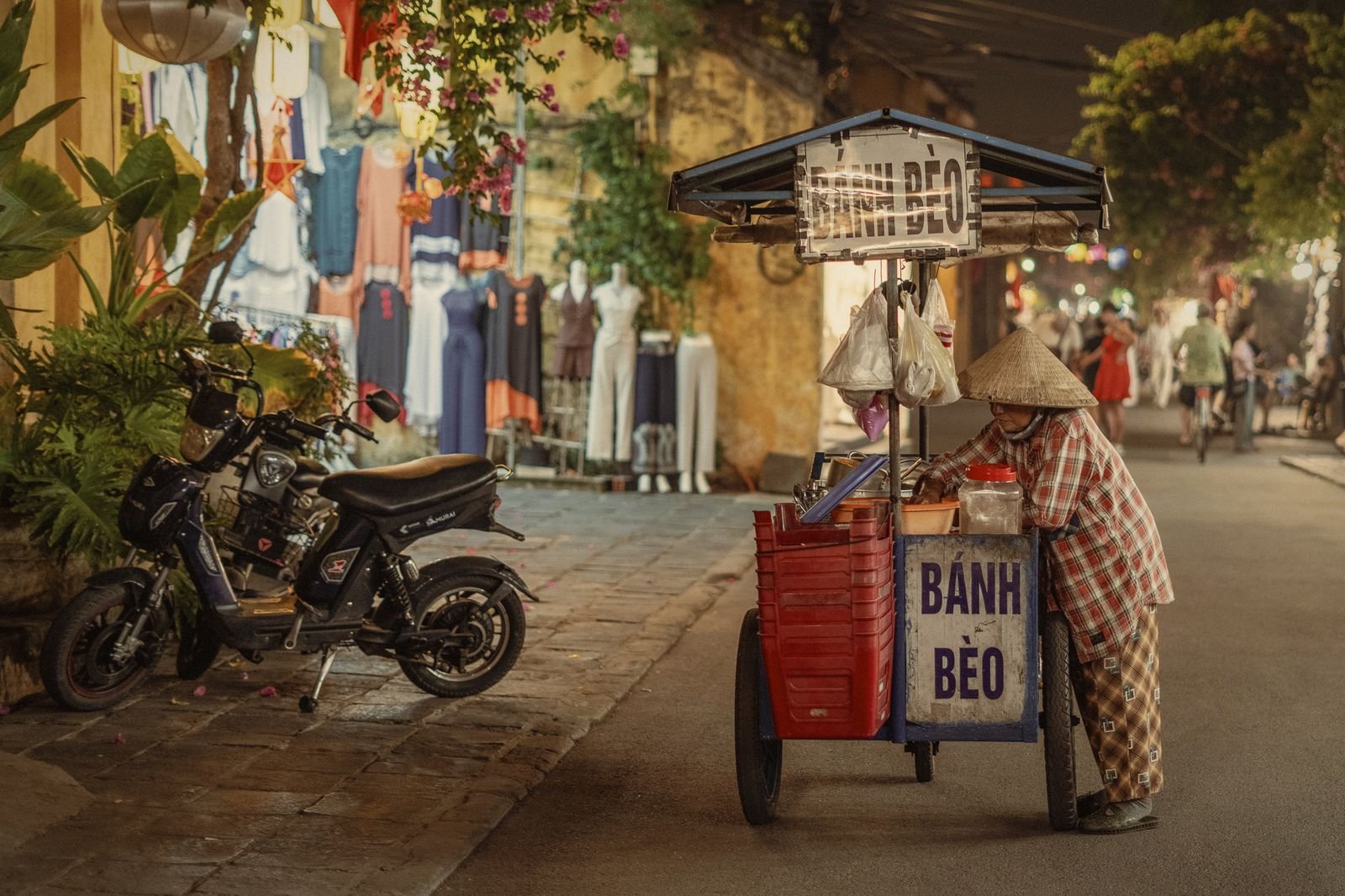 A street cart selling banh beo on a yellow-walled Hoi An street