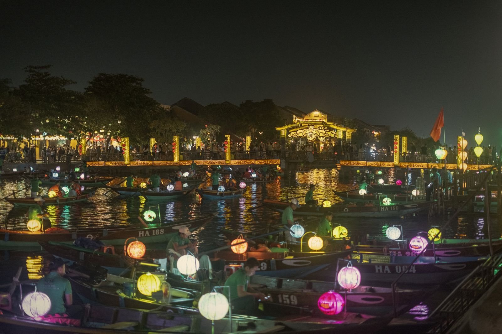 Boats carrying coloured lanterns across the Hoi An river at night