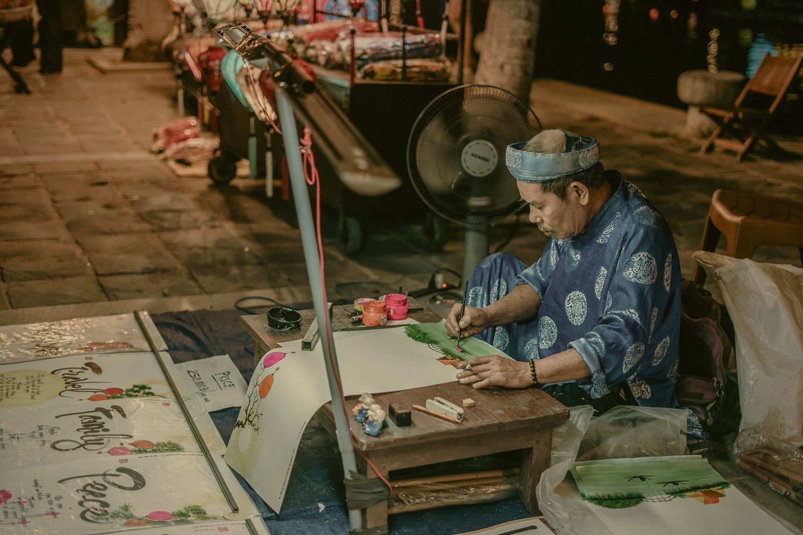 A craftswoman painting lanterns by hand at her workbench in Hoi An, Vietnam