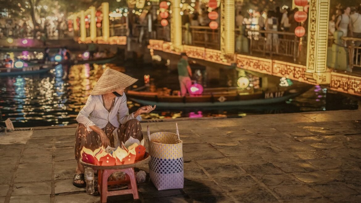 Lantern seller on the Thu Bồn riverbank in Hội An at blue hour, a highlight of this Thailand Vietnam itinerary