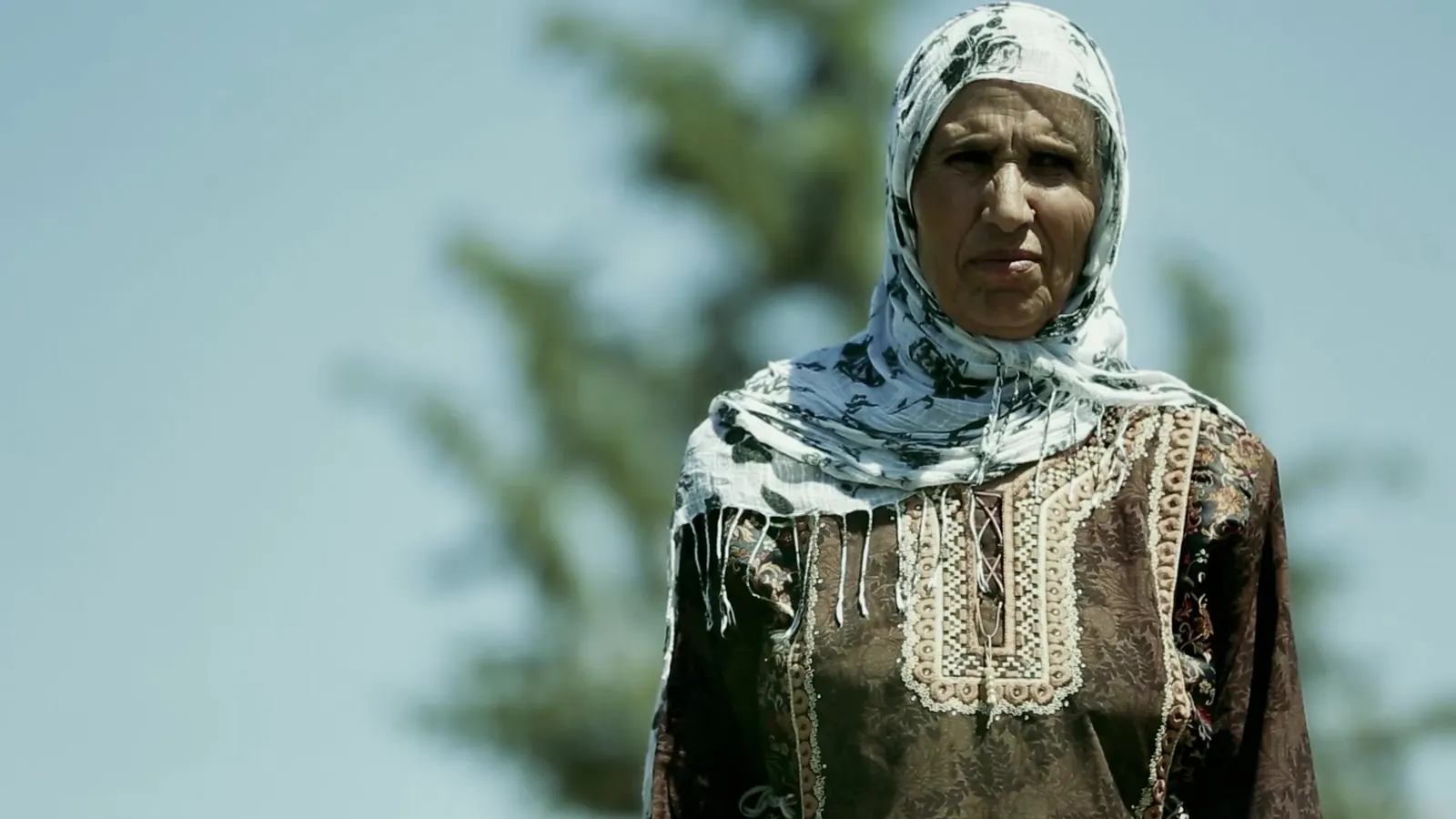 Portrait of a woman in a patterned headscarf against the sky, still from the ILO documentary films in Tunisia
