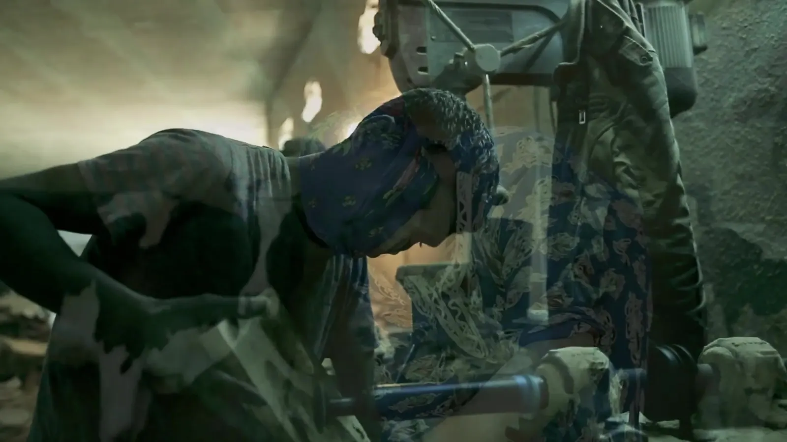 Documentary still from the ILO decent work films in Tunisia: a worker bent over machinery in a small workshop lit by daylight