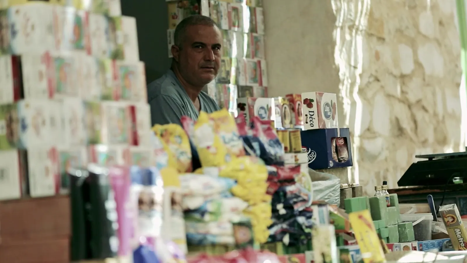Decent Work, Up Close: ILO Documentary Films 8 A shopkeeper standing behind a counter in a small grocery shop stacked with goods