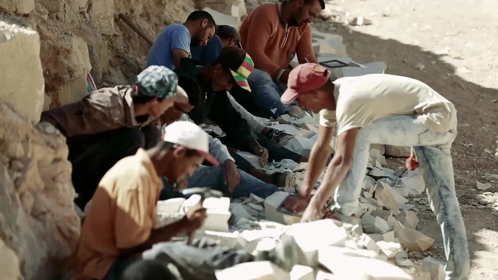 Decent Work, Up Close: ILO Documentary Films 11 A group of workers crouched together cutting and stacking stone blocks at a quarry