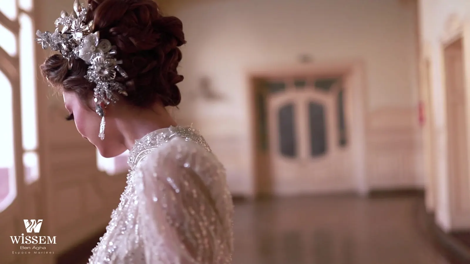 Bride glancing over her shoulder in a beaded gown with a floral hair ornament, carved doors behind