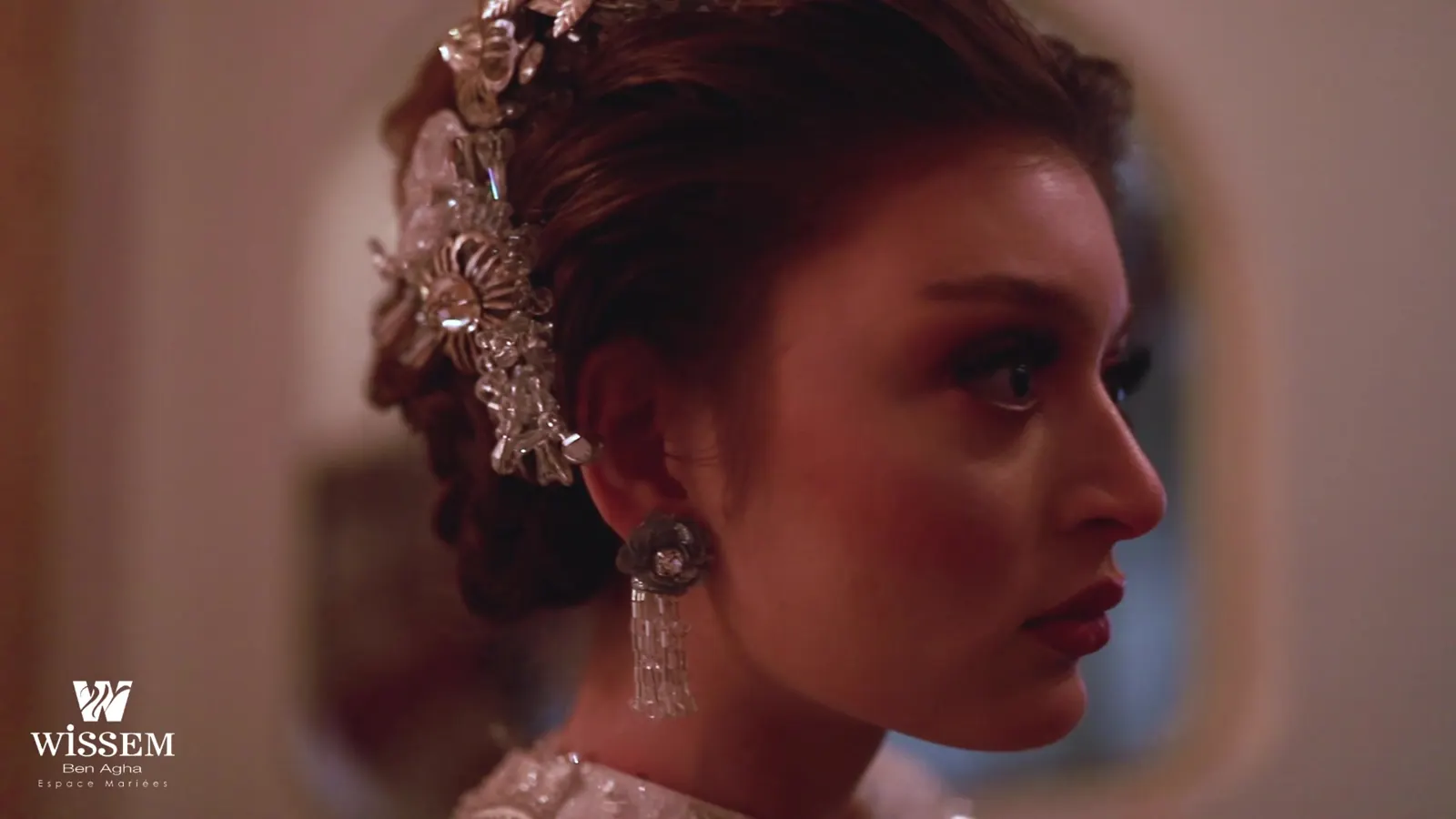 Close portrait of a bride in profile with a jewelled floral hair piece and statement earrings
