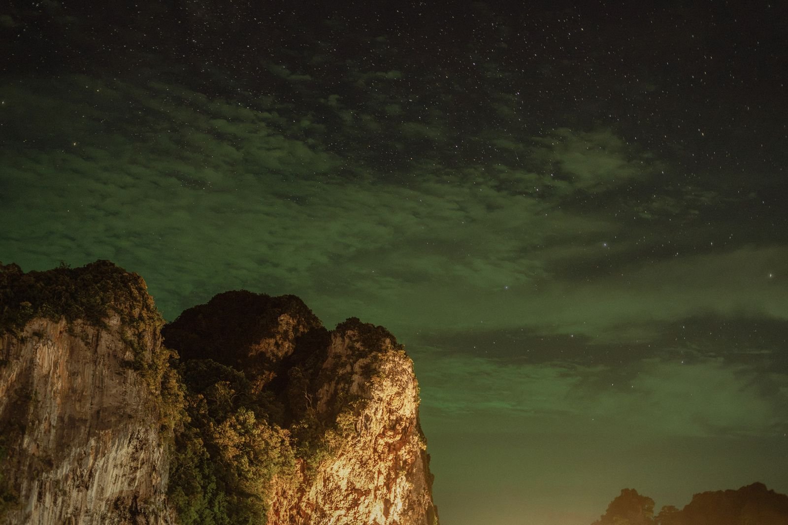 Krabi limestone cliffs lit warm against a green night sky
