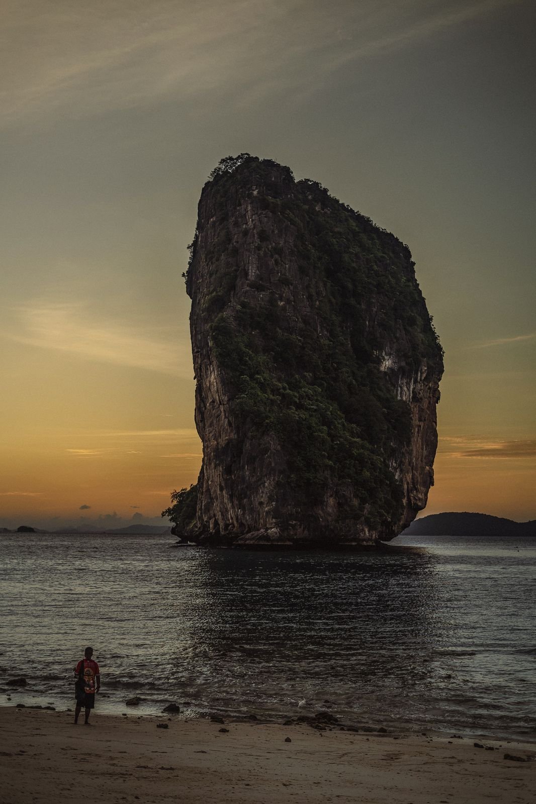 A limestone sea stack silhouetted against a Krabi sunset