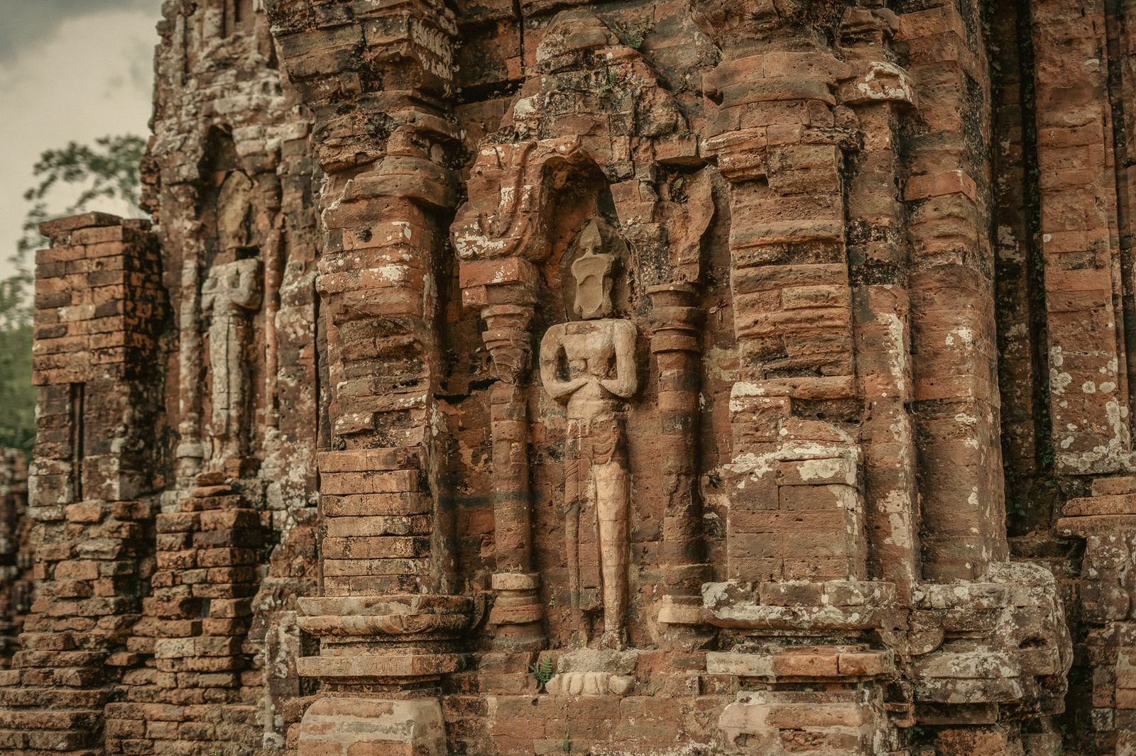 A carved deity relief on a Cham brick wall at My Son
