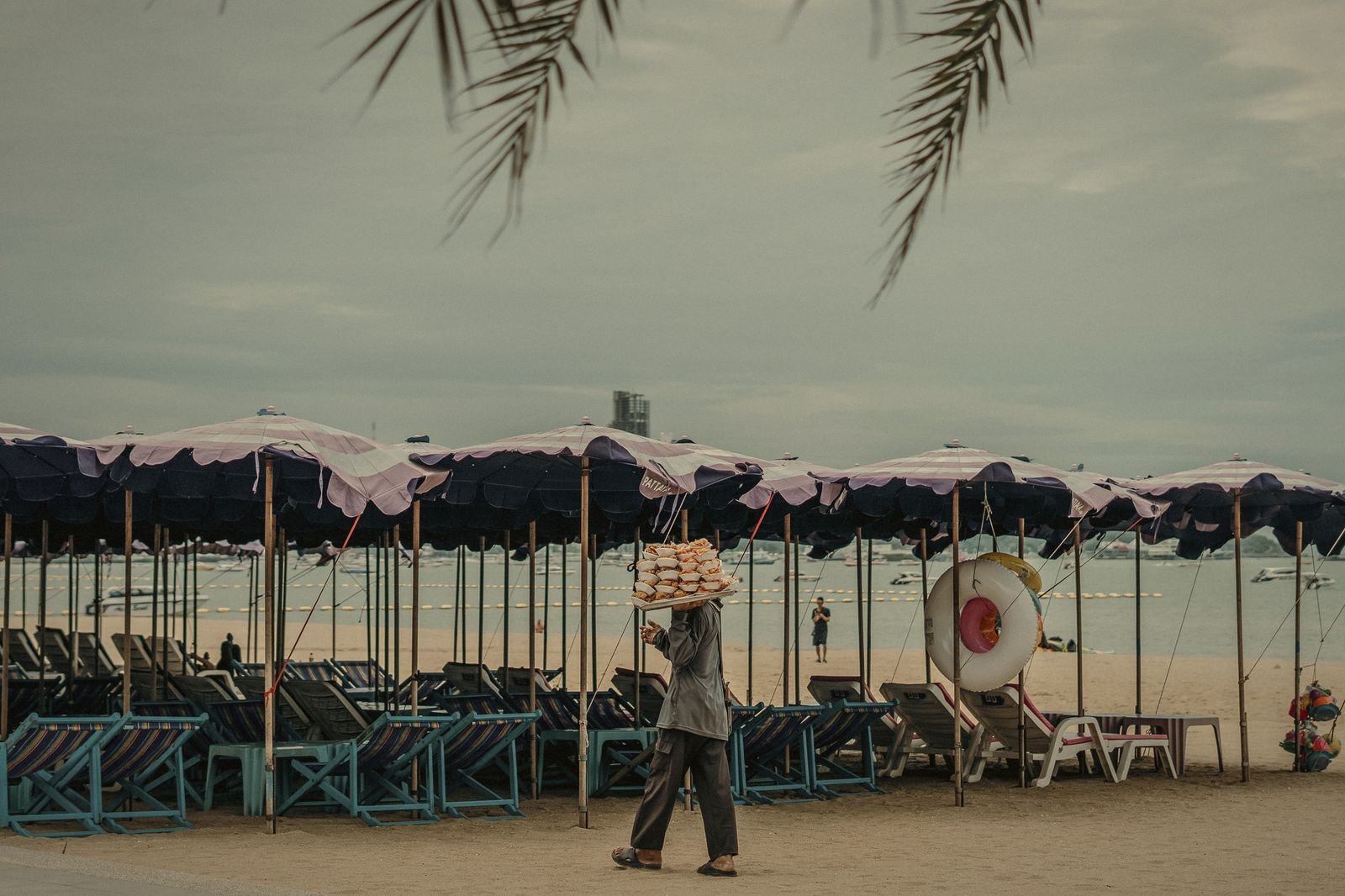 A beach vendor walking past rows of umbrellas in Pattaya