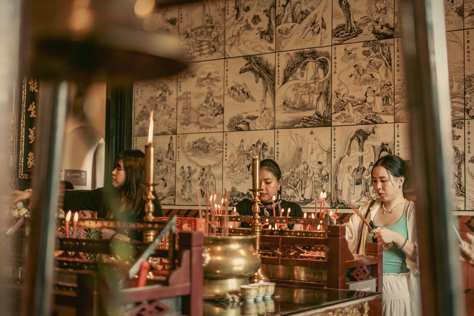 Women at a candle-lit altar inside a Phuket Chinese shrine, Thailand